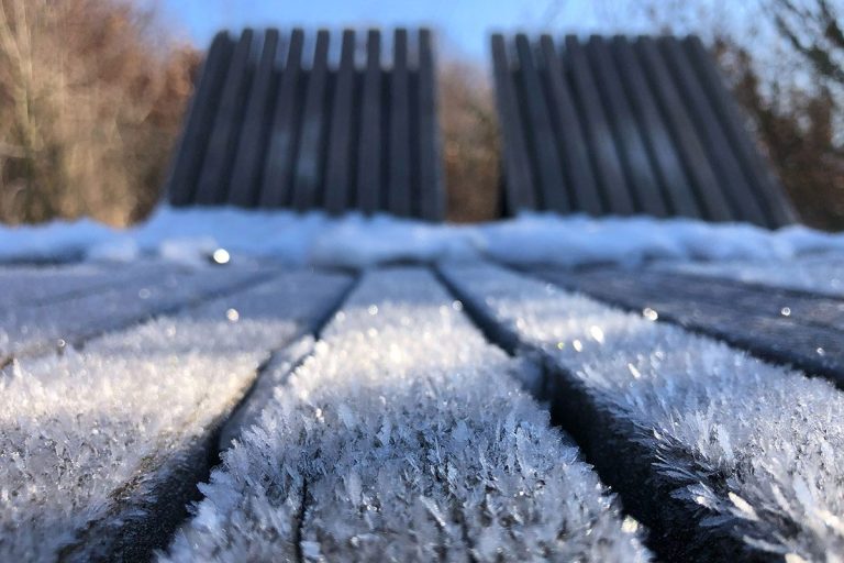 Das Foto zeigt Eiskristalle auf den Holzplanken einer Liege.