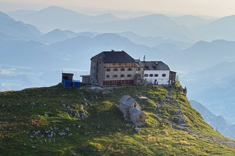 Das Foto zeigt das Watzmannhaus vor einer atemberaubenden Bergkulisse von etwas oberhalb gesehen, während des Aufstiegs zum Watzmanngipfel.
